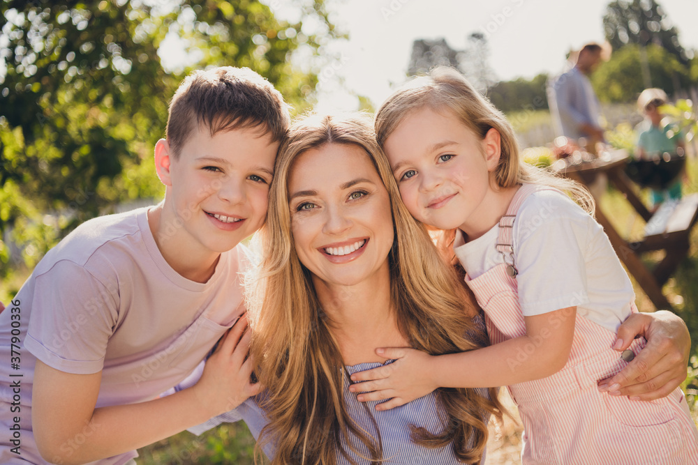 Photo of positive mom mommy and her small kids hug embrace enjoy outside city summer garden relax weekend have sunshine sunset sky