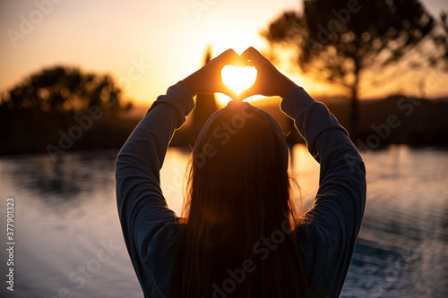 Silhouette of a woman making a heart sign with hannds photo