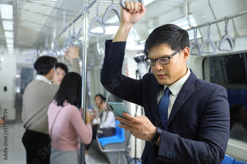 A lifestyle of Asian man wearing formal using cellphone while taking the subway train to work at the rush hour morning with copy space