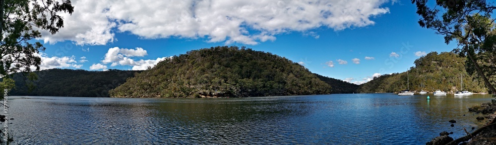 Beautiful morning panoramic view of a creek with reflections of blue sky, boats, mountains and trees, Apple Tree Creek, Bobbin Head, Ku-ring-gai Chase National Park, New South Wales, Australia
