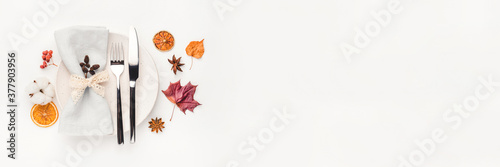 Thanksgiving autumn background. Plate with Cutlery and napkin decorated with autumn leaves, berries and spices. Top view.