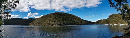 Beautiful morning panoramic view of a creek with reflections of blue sky, boats, mountains and trees, Apple Tree Creek, Bobbin Head, Ku-ring-gai Chase National Park, New South Wales, Australia 