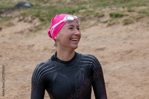 Woman swimmer-athlete in wetsuit and hat smiling. Sports swimming, triathlon