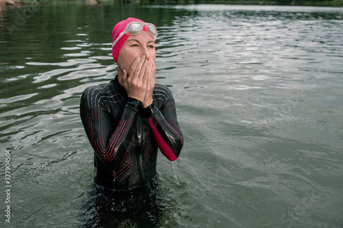 Girl swimmer athlete stands in the lake. Sports swimming triathlon.
