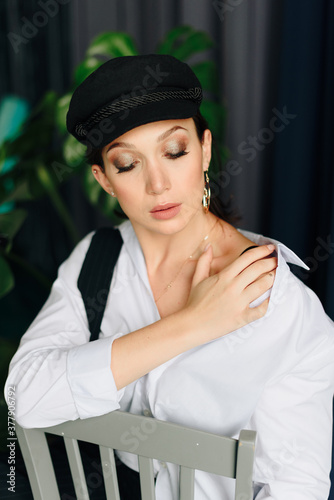 Portrait of a beautiful young woman in a white shirt and black pants in the Studio