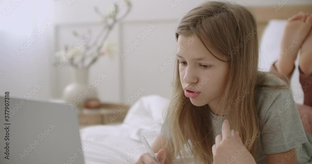 funny preteen girl is talking by video calling on laptop, staying home and learning online