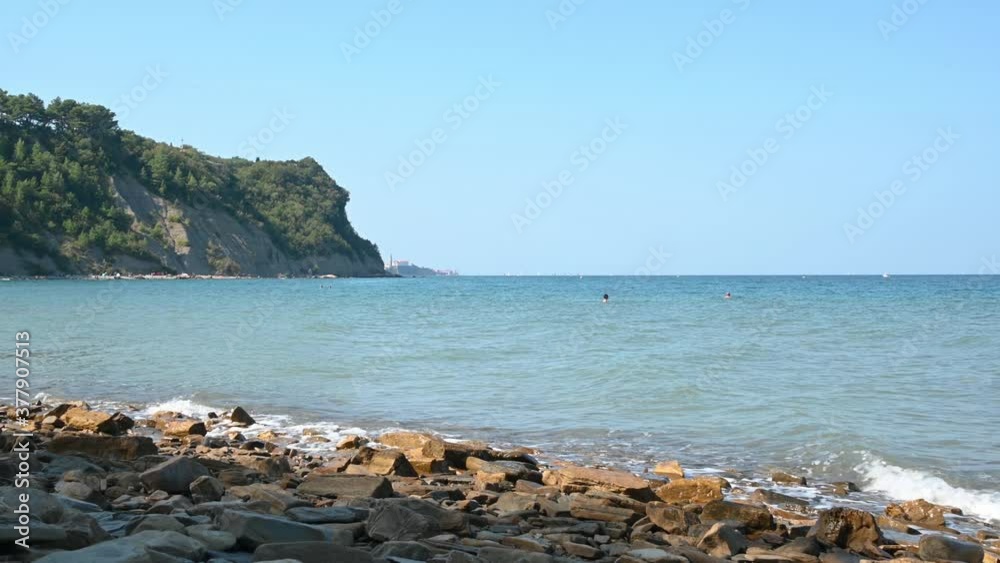Beautiful Moon Bay in Slovenia on hot summer day. The waves hit the rocky shore. People enjoying in Adriatic Sea. Left pan, wide, real time, 4K Beautiful Moon Bay in Slovenia on hot summer day. The waves hit the rocky shore. People enjoying in Adriatic Sea. Left pan, wide, real time, 4K