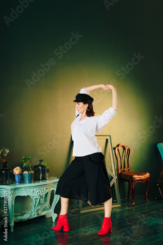 Portrait of a beautiful young woman in a white shirt and black pants in the Studio