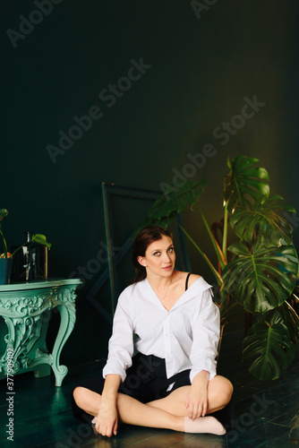 Portrait of a beautiful young woman in a white shirt and black pants in the Studio