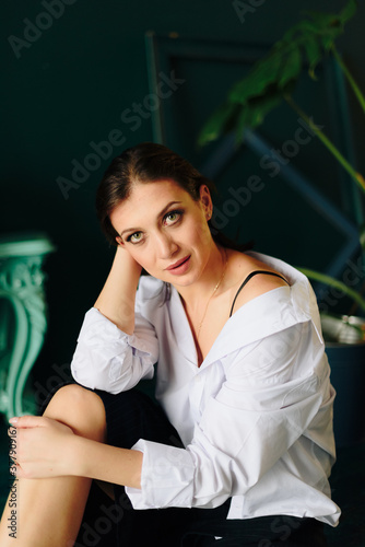 Portrait of a beautiful young woman in a white shirt and black pants in the Studio