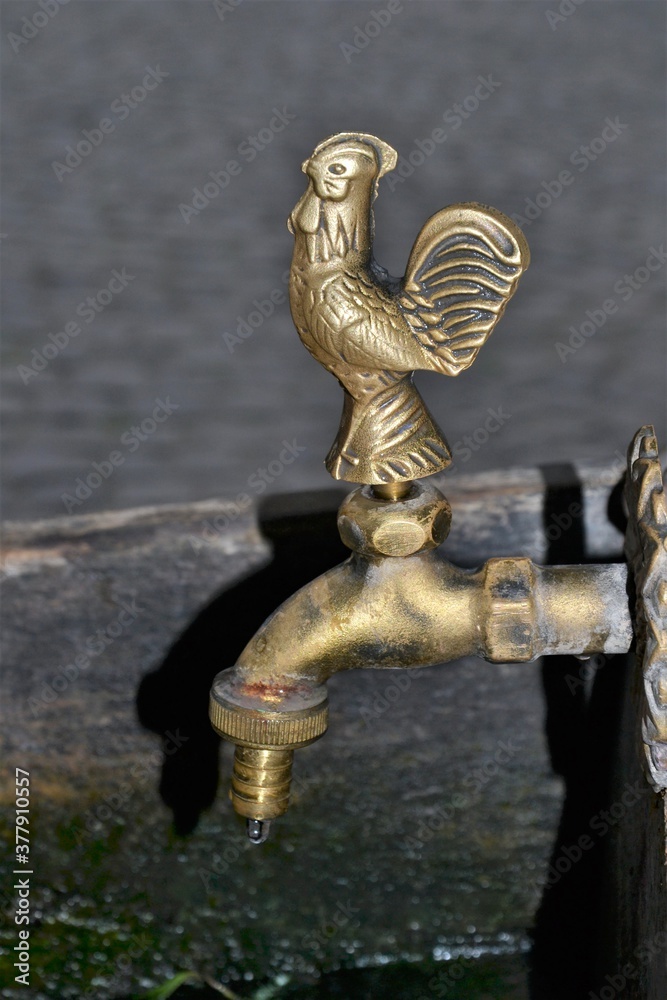 Water faucet or tap with a bronze figure of a rooster. Details of the wooden well in Kazimierz Dolny, Poland. An artistic tap at the well Water faucet or tap with a bronze figure of a rooster. Details of the wooden well in Kazimierz Dolny, Poland. An artistic tap at the well