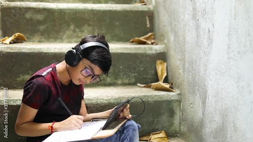 Indian / Asian Little boy studying online using mobile phone at home