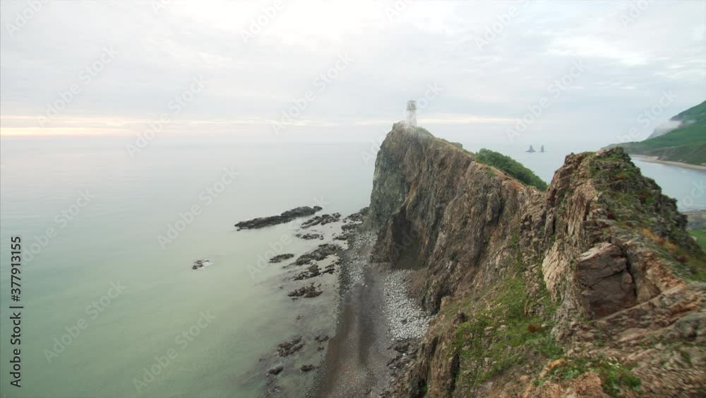Timelapse of a high cliff above the sea and the path leading to the lighthouse on its top. Light morning fog. Far East of Russia Timelapse of a high cliff above the sea and the path leading to the lighthouse on its top. Light morning fog. Far East of Russia