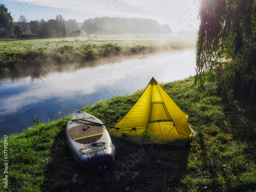Canvas-taulu SUP (Stand up paddling) board next to a small tent at river Ilmenau on a camp si
