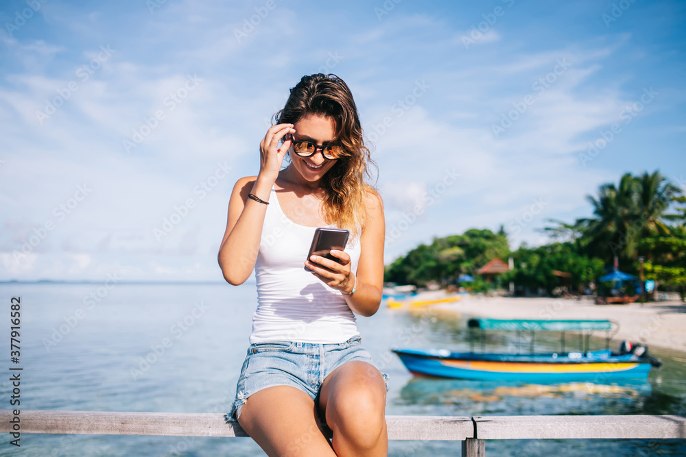 Happy adult woman using smartphone at sea