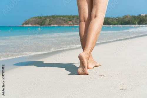 Young Asian woman walking on sand beach. Closeup detail of female feet and white sand at Phuket, Thailand. Beach travel concept.