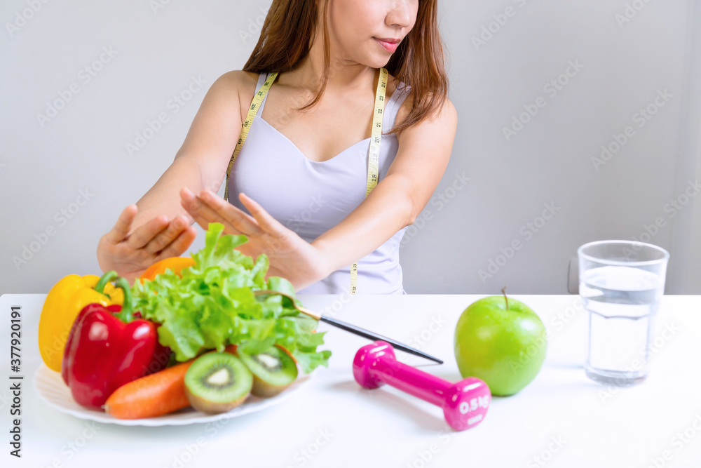 Hands of unhappy Aisan woman push out vegatables and fruits with bored emotion on dieting time. Healthy food concept. Close up