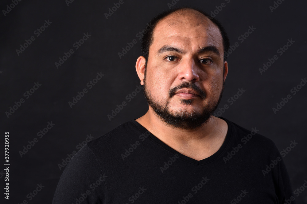 portrait of a latin american man on black  background,serious
