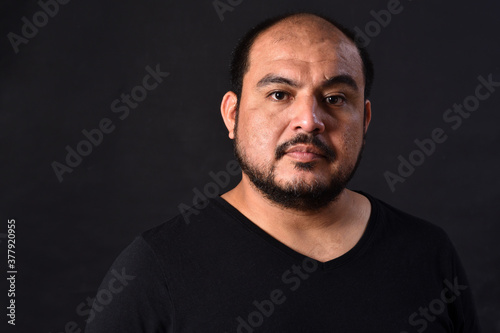 portrait of a latin american man on black background,serious