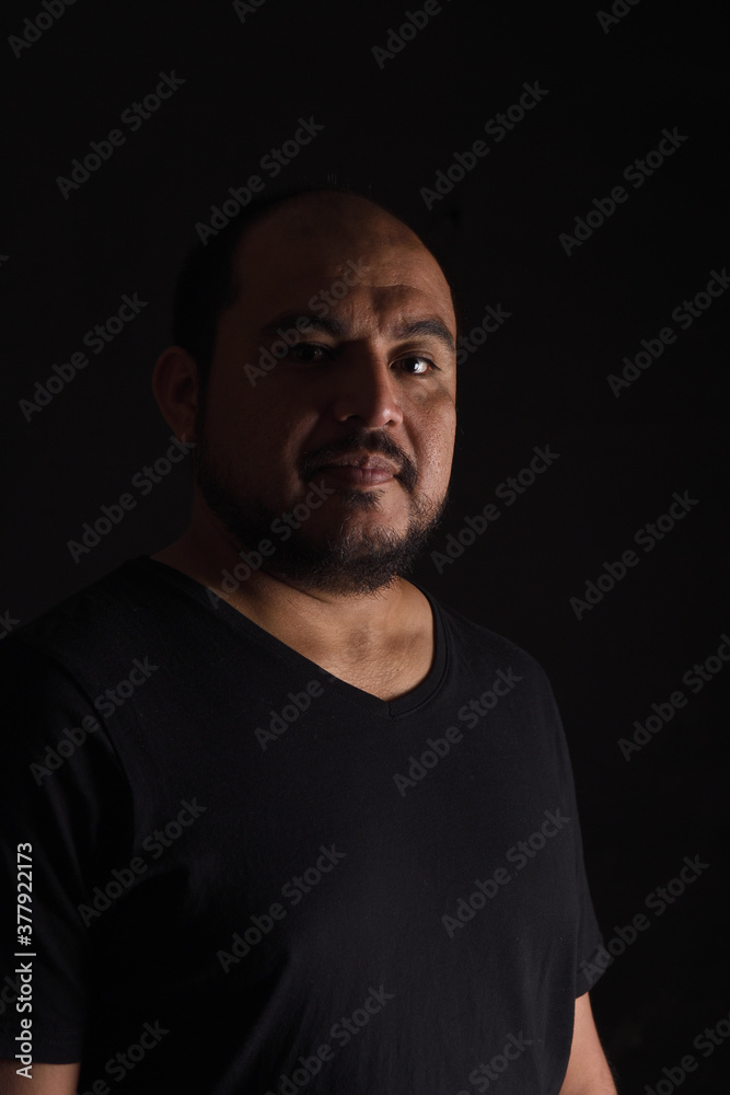 dark side view portrait of a latin american man on black  background