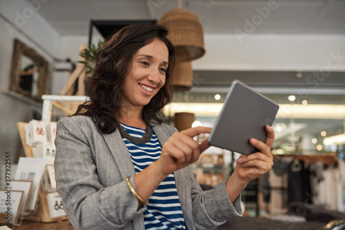 Smiling Asian woman working on a tablet in her shop