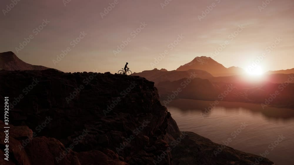 WIDE Caucasian female enjoying sunset on a cliff near lake during bicycle ride WIDE Caucasian female enjoying sunset on a cliff near lake during bicycle ride