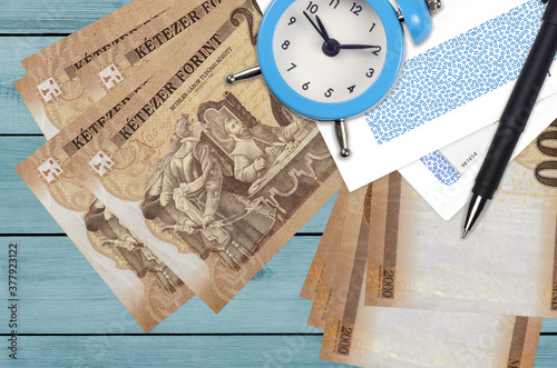 2000 Hungarian forint bills and alarm clock with pen and envelopes. Tax season concept, payment deadline for credit or loan. Financial operations using postal service photo