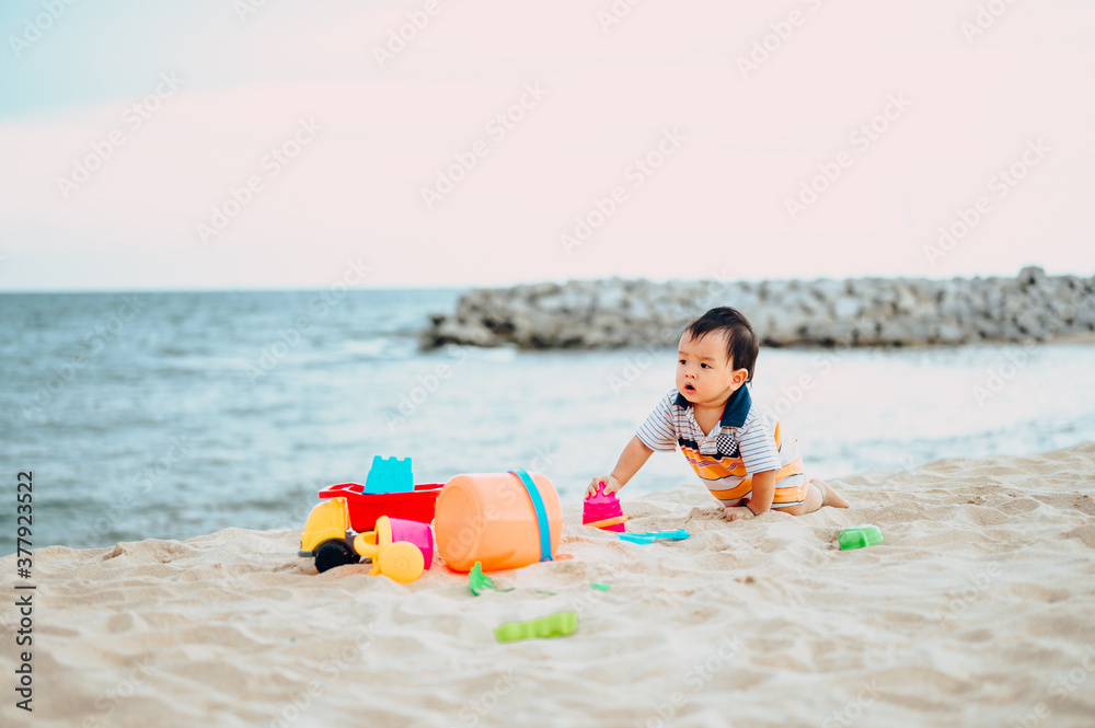 Baby boy playing with beach toys with his mother on tropical beach.Summer family vacation Baby boy playing with beach toys with his mother on tropical beach.Summer family vacation