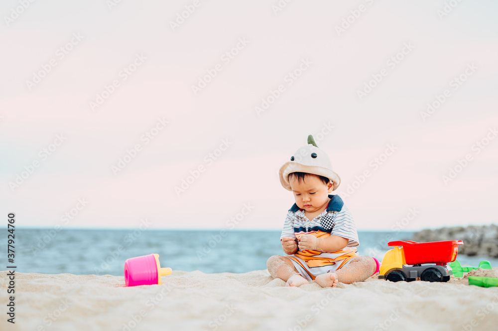 Baby boy playing with beach toys with his mother on tropical beach.Summer family vacation