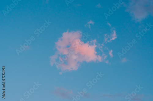 one irregular shaped pink cloud against deep blue sky on the background