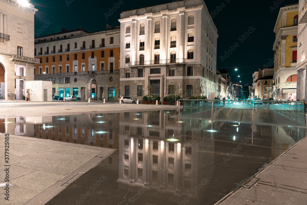 Urban movement in a night square. Victory Square, Brescia, Italy..