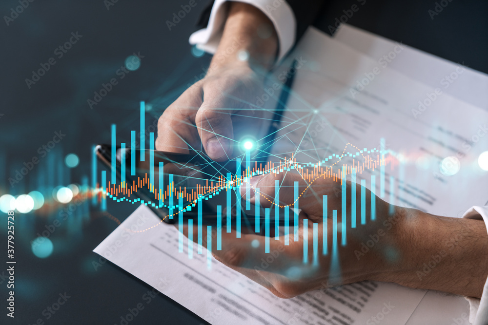 Businessman trading stocks using on-line app on phone. Financial graph hologram. Businessman trading stocks using on-line app on phone. Financial graph hologram.