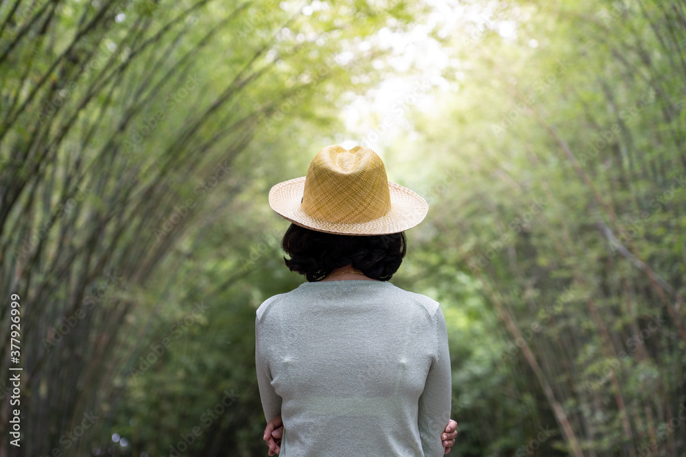 Woman in a cowboy hat is watching the bamboo garden.