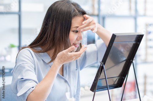 Asian woman trying to put contact lenses into her eyes