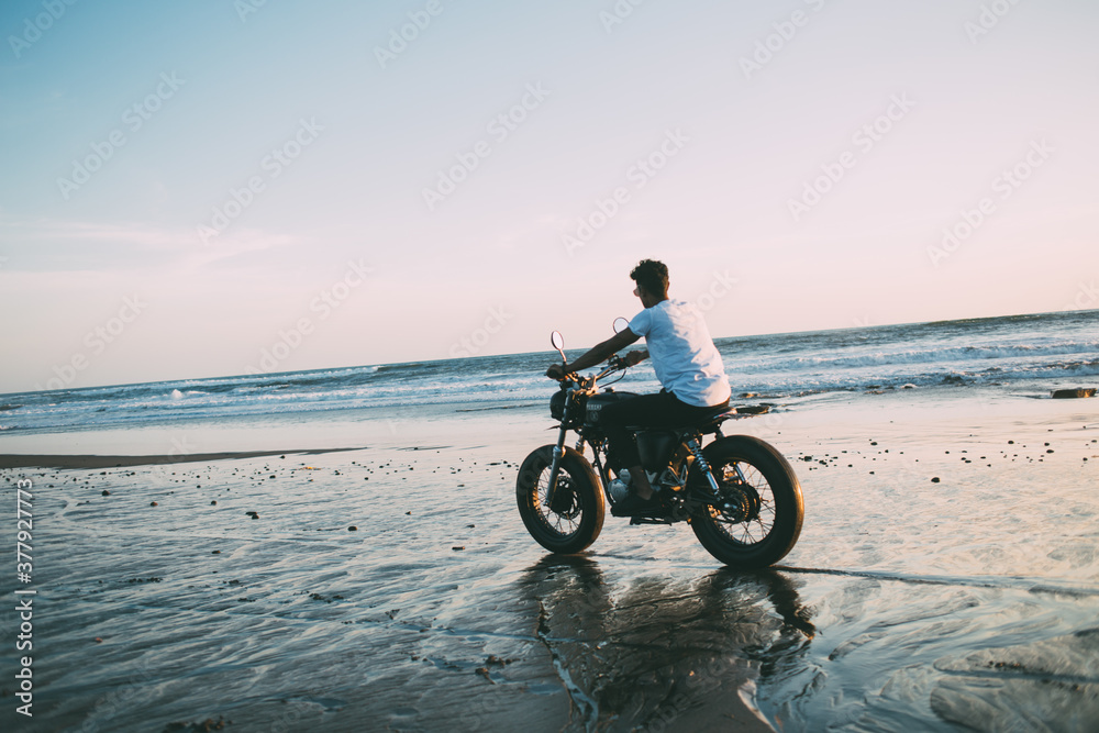 Male motorcyclist riding bike on seashore