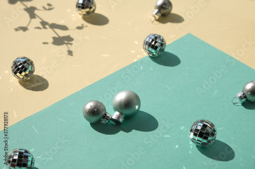 Mirror balls and silver Xmas baubles on mint green and yellow layered paper. Geometric Christmas background, isometric view with shadows photo