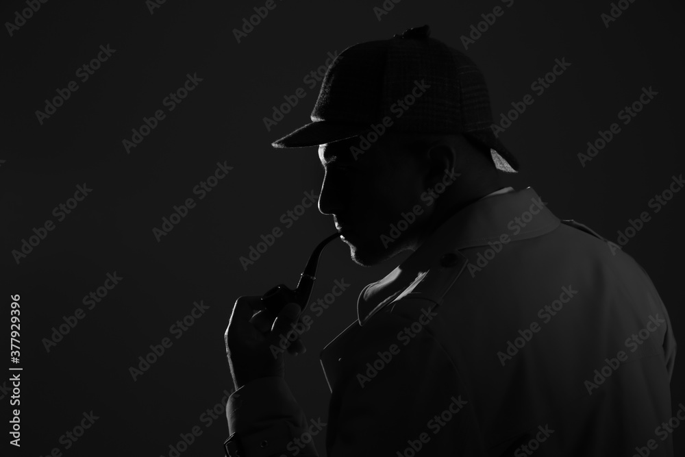 Old fashioned detective with smoking pipe on dark background, black and white effect Old fashioned detective with smoking pipe on dark background, black and white effect