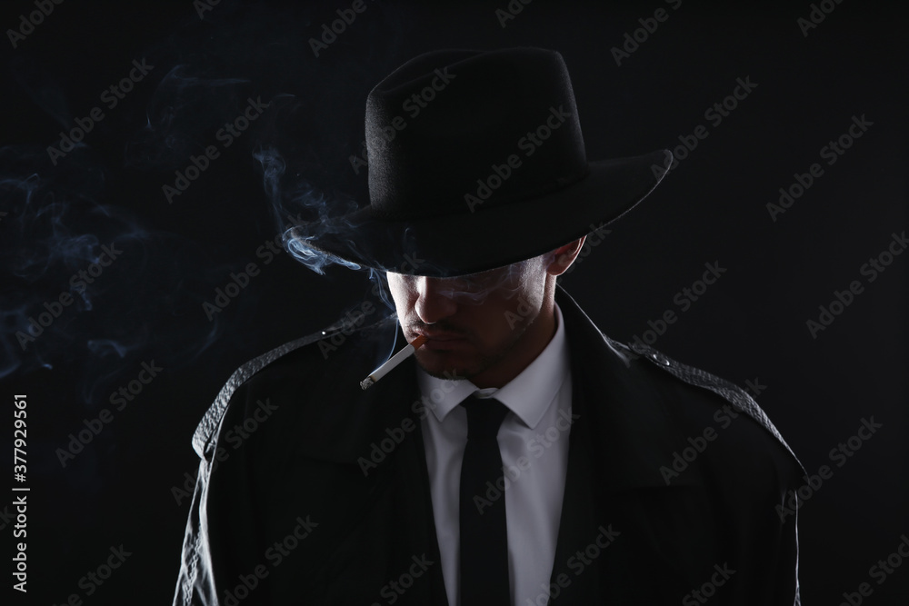 Old fashioned detective smoking cigarette on dark background