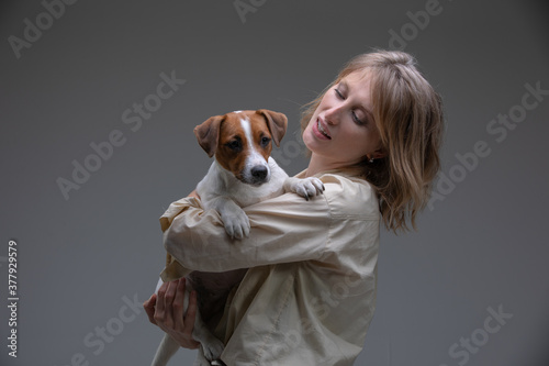 Pretty woman holds her puppy on shoulder