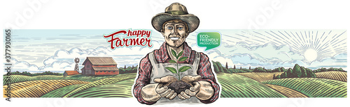 Happy farmer holds a young plant shoot in his hands, against the background of an agricultural landscape.