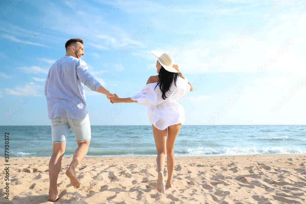 Happy couple running together on beach, back view Happy couple running together on beach, back view