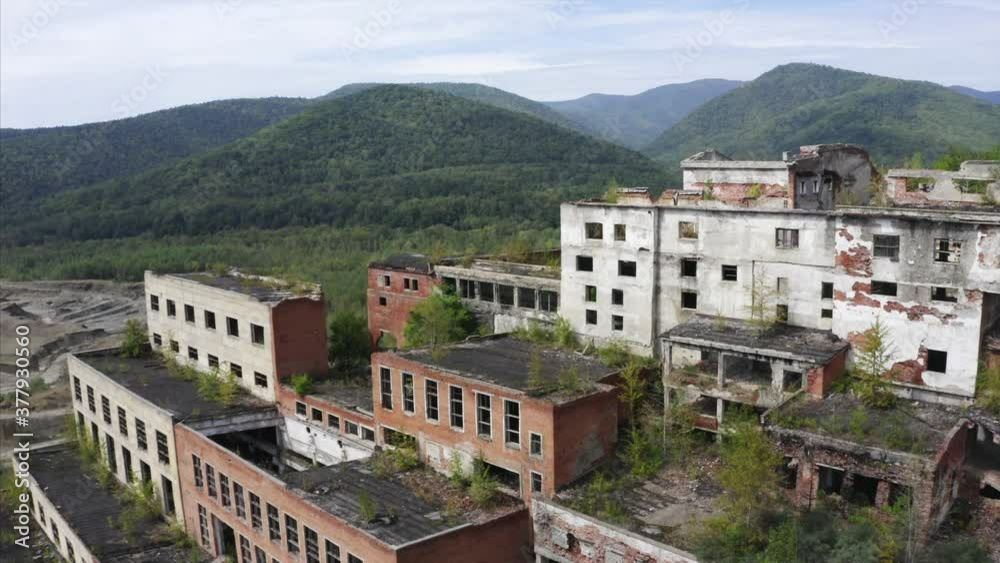 Aerial zooming in view of old destroyed ore dressing and mineral dressing factory at Far East of Russia. Green hills are on the background Aerial zooming in view of old destroyed ore dressing and mineral dressing factory at Far East of Russia. Green hills are on the background