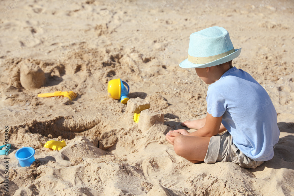 Cute little boy playing with plastic toys on sandy beach Cute little boy playing with plastic toys on sandy beach