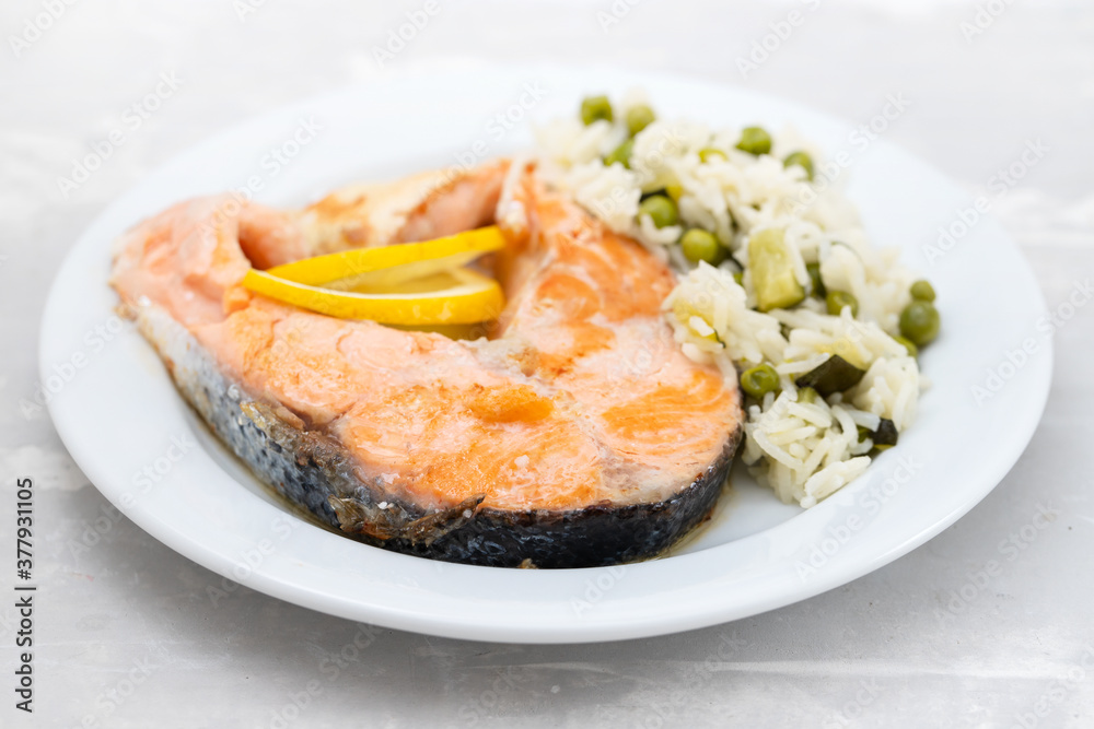 fried salmon with rice with vegetables on white plate on ceramic background fried salmon with rice with vegetables on white plate on ceramic background