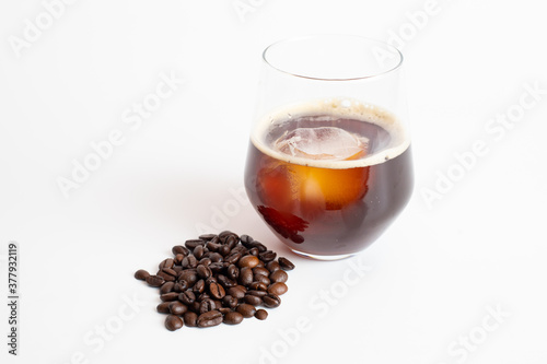 A glass of coffee and coffee beans on white background