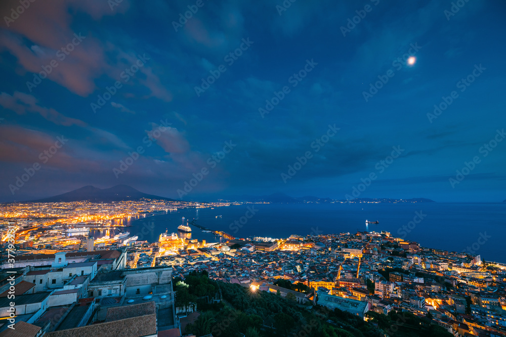 Naples, Italy. Skyline Cityscape In Evening Lighting. Tyrrhenian Sea And Landscape With Volcano Mount Vesuvius. City In Night Illuminations