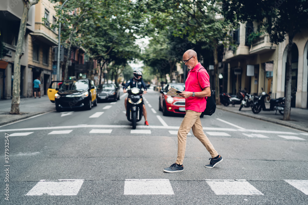 Elderly male pedestrian with backpack crossing street