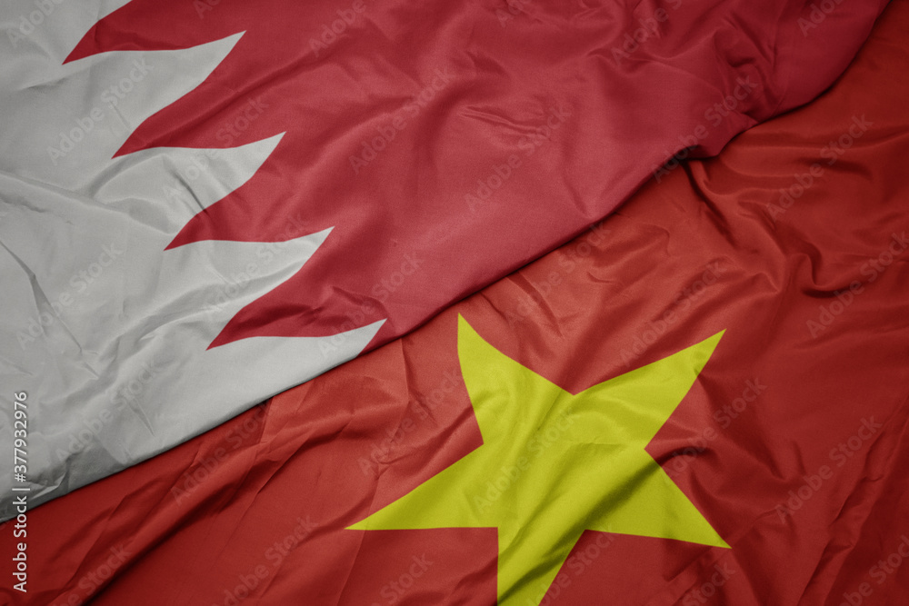waving colorful flag of vietnam and national flag of bahrain.