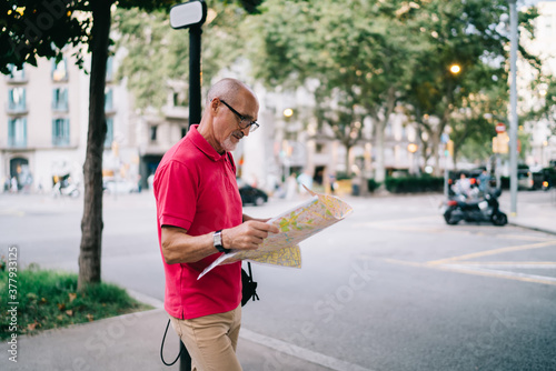 Focused senior male tourist with map on street
