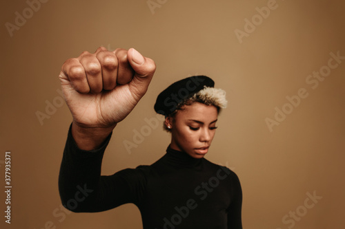 Foto African american woman with raised fist on brown background